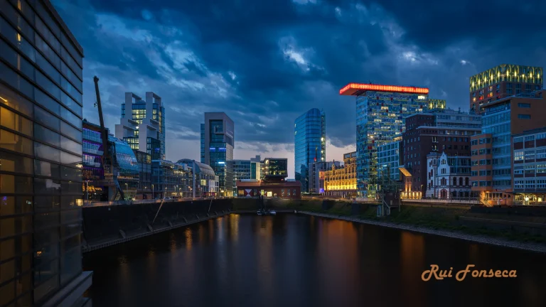 Night cityscape with a river reflecting the lights of modern buildings.