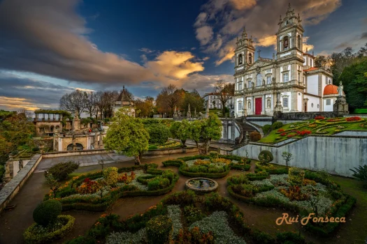 A picturesque view of the Church of Santa Clara and its formal gardens at sunset.