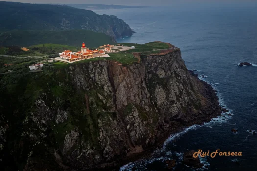 Aerial view of the Cabo da Roca lighthouse perched dramatically on a cliff overlooking the Atlantic Ocean.