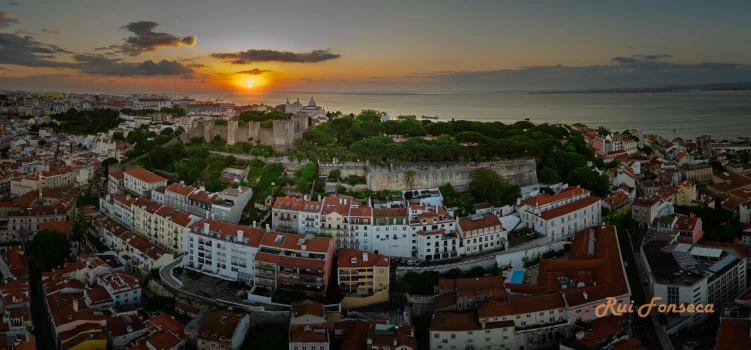 Aerial view of Lisbon, Portugal at sunset, showcasing the São Jorge Castle and surrounding cityscape.