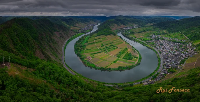 Aerial view of a lush green landscape with a river and a viewpoint structure.