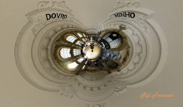A symmetrical, upward-looking photograph of a highly ornate ceiling with inscriptions and a central chandelier.