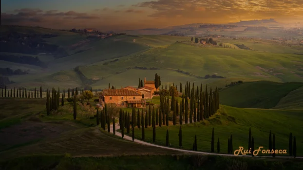 A picturesque Tuscan landscape at dawn, featuring a stone farmhouse surrounded by a cypress-lined driveway, rolling hills, and a dramatic sky.