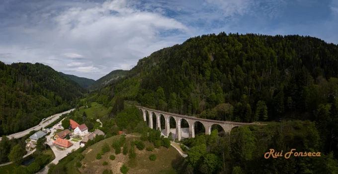 Aerial view of a valley with a highway, village, and lush greenery.