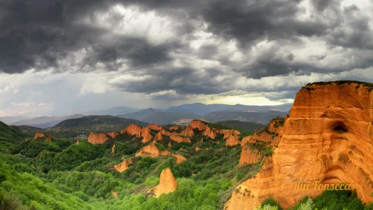 Panoramic view of the surreal rock formations of Cappadocia, Turkey, under a dramatic, cloudy sky.