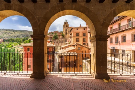 A view of the historic town of Covadonga, Spain, framed by a stone archway.